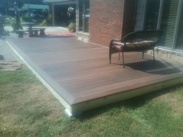 New wood deck and wicker chair beside a brick house in Walnut Bottom