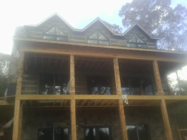 Dormers and porch framing on a large log home under construction — Roof Coating work by our crew in Walnut Bottom