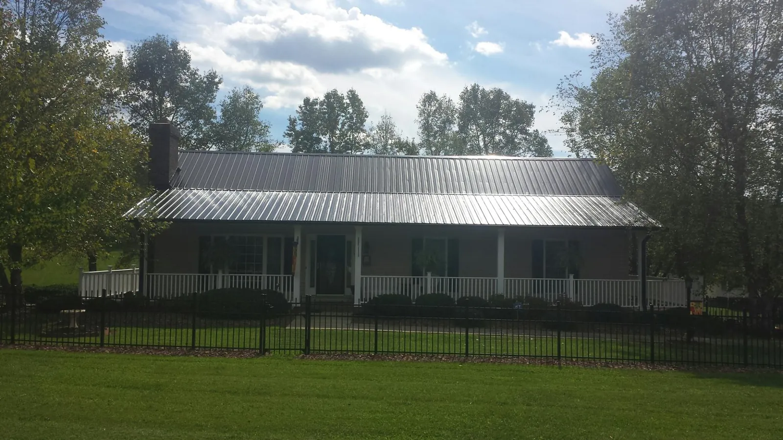 Gray metal roof on a brick ranch with a full width front porch — Gutter Guard Installation work by our crew in Walnut Bottom