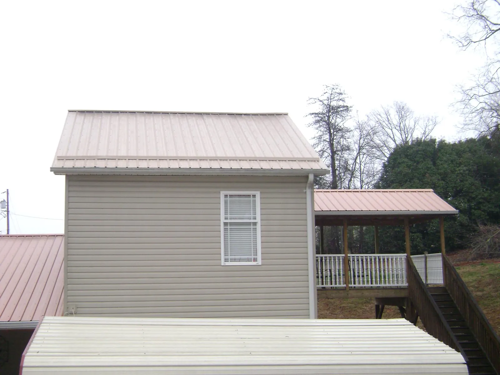 Tan metal roofs on a two story addition and attached porch, from a Roof Replacement job in Walnut Bottom
