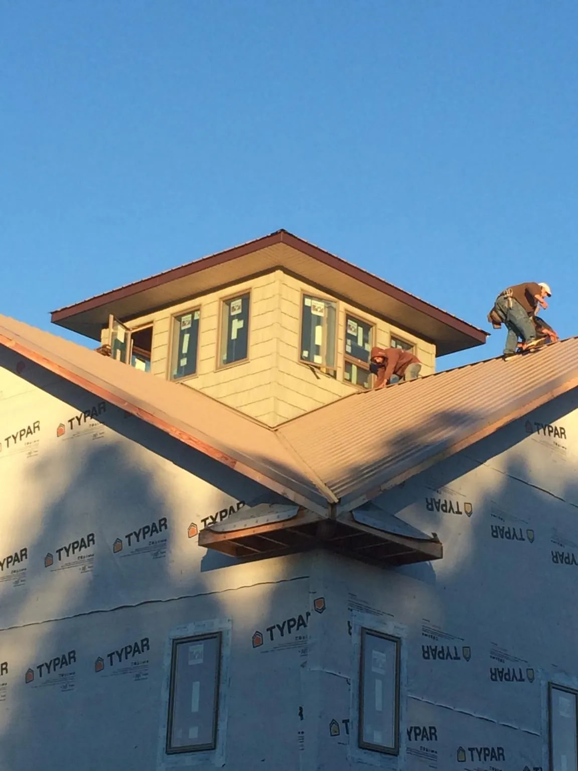 Roofers working around a rooftop cupola on a new metal roof at sunset — Roof Waterproofing in Walnut Bottom by Roofing Brothers